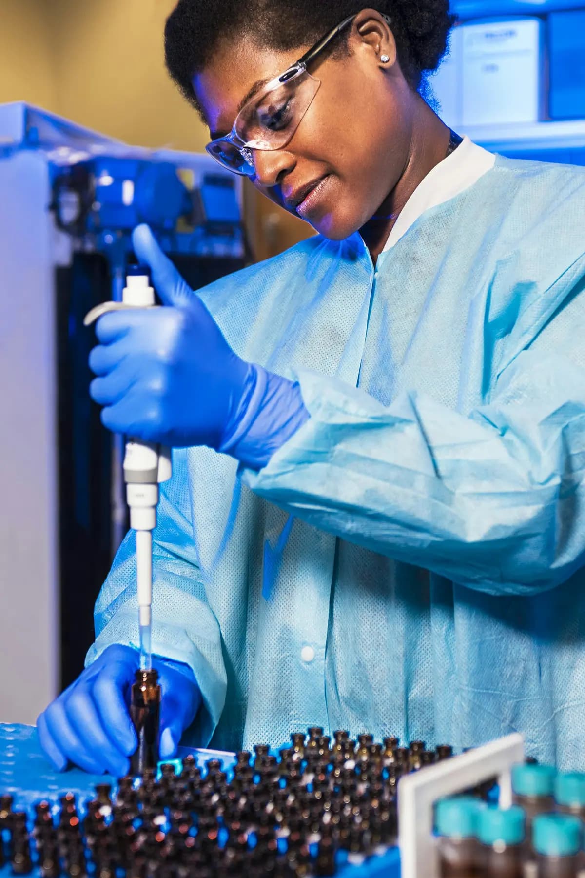 A laboratory technician in gloves using a pipette