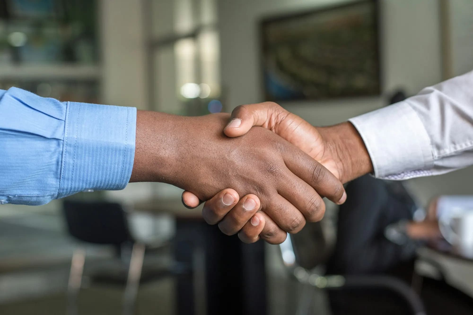 Two people shaking hands across a desk